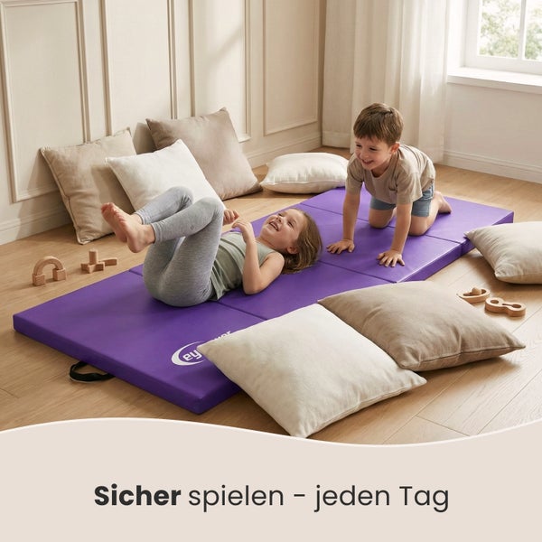 Zwei Kinder spielen auf einer violetten Turnmatte, umgeben von Kissen und Holzspielzeug.