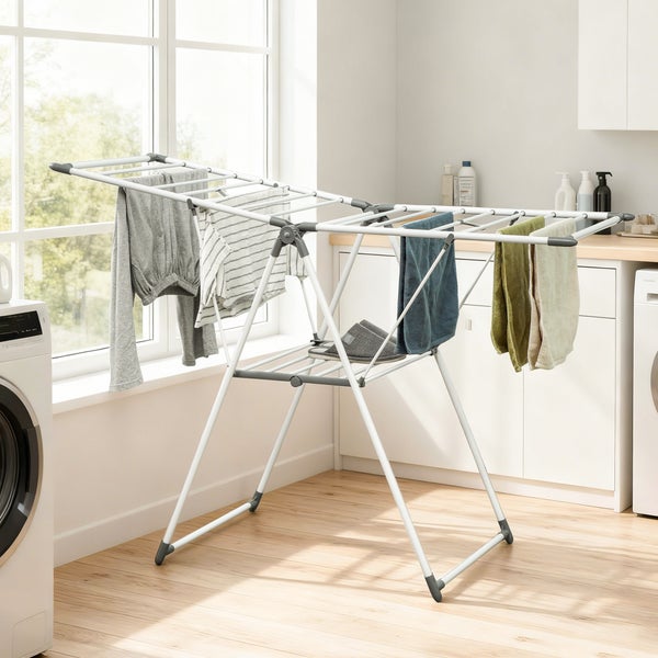 Klappbarer Flügelwäscheständer in einer hellen Waschküche mit aufgehängter Wäsche vor einem großen Fenster.