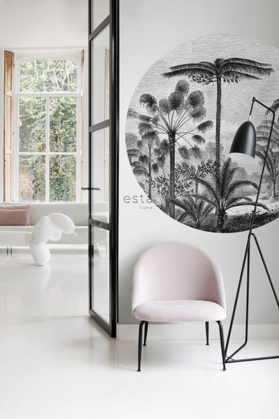 Heller Raum mit Sessel, Stehlampe und Wanddeko mit Palmenmotiv