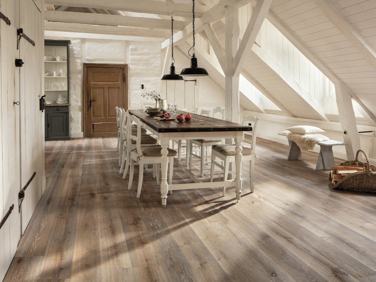 Heller, geräumiger Essbereich im Dachgeschoss mit breitem Echtholzparkett, Holzbalken an der Decke und einem großen Esstisch im Landhausstil.