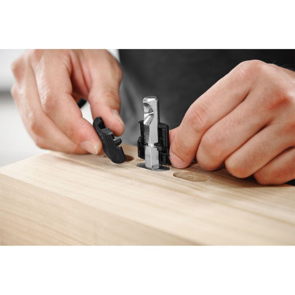 Eine Person setzt einen Dübelbohrer in eine Holzplatte ein.