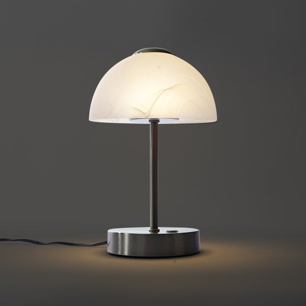 Moderne Tischleuchte mit gebürstetem Metallsockel und weißem, marmoriertem Glasschirm in Pilzform.