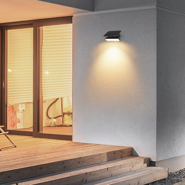 Solarleuchte an einer Hauswand über einer Holzterrasse