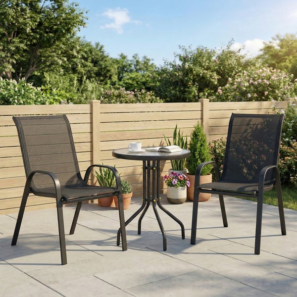 Gartenmöbel-Set aus zwei Gartenstühlen mit Netzbespannung und einem runden Glastisch auf einer hellen Terrasse mit Holzzaun.