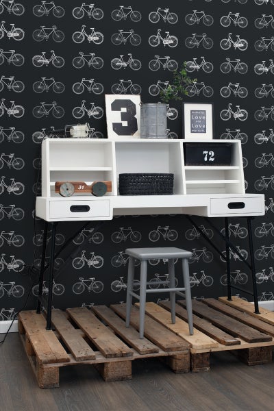 Schreibtisch mit Stuhl vor einer Wand mit Fahrradmuster