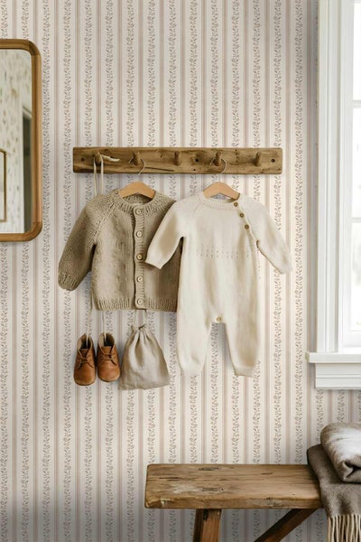 Kinderzimmer mit gestreifter Tapete mit floralem Muster, einer Holzgarderobe mit Babykleidung, Spiegel und Holzbank.
