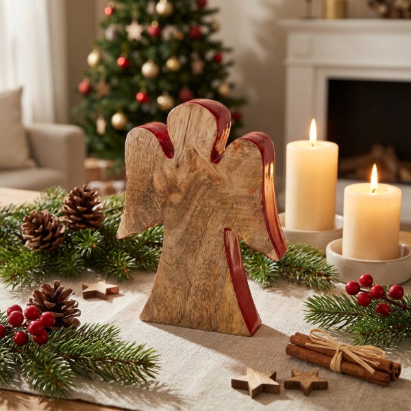 Weihnachtsdekoration Holzengel auf festlich gedecktem Tisch mit Tannenzweigen und Kerzen