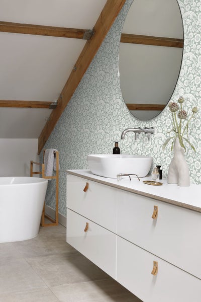 Badezimmer mit floraler Tapete, Waschbecken, Spiegel und weißen Unterschränken