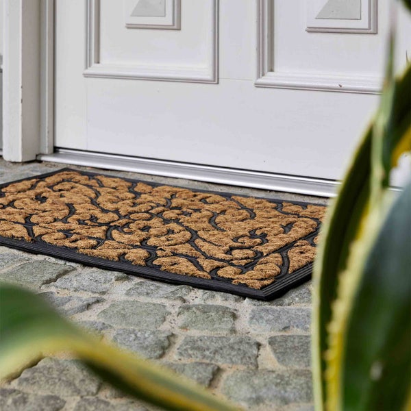 Fußmatte aus Kokosfaser mit Muster vor einer Tür