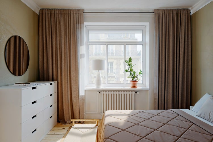 Helles Schlafzimmer mit Bett, Fenster, Kommode und Vorhängen