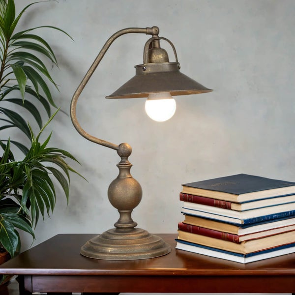 Dekorative Tischleuchte aus Metall auf einem Tisch mit Büchern und Pflanze