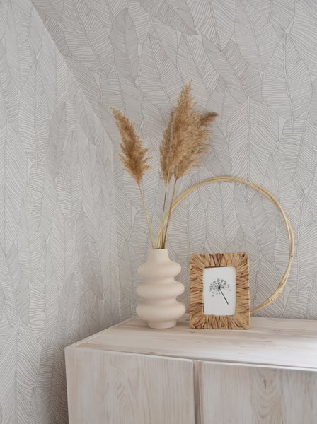 Dekorative Szene mit Vase, Trockenblumen und Bilderrahmen auf einem Schrank