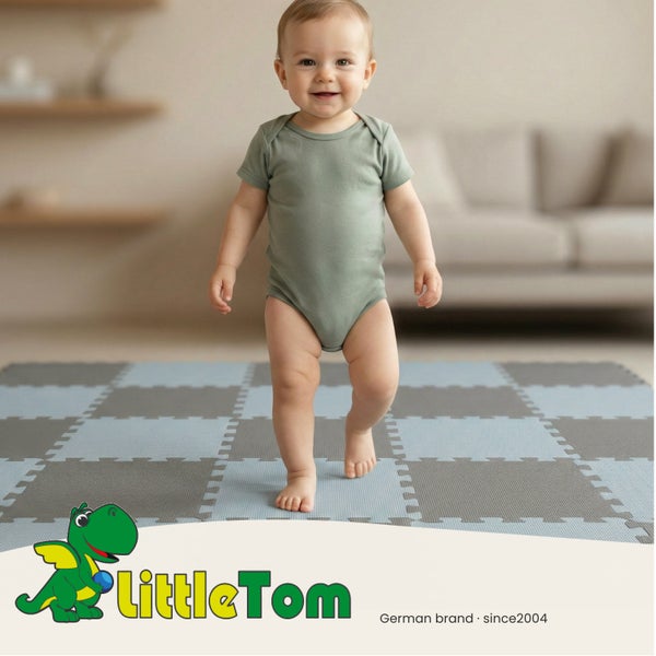 Ein Kleinkind steht auf einer blau-grau karierten LittleTom Puzzlematte aus Schaumstoff in einem hellen Wohnzimmer. LittleTom Logo.
