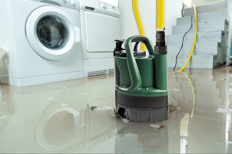 Kellerraum mit Waschmaschine, Trockner, Treppe und überflutetem Boden, im Vordergrund eine Schmutzwasserpumpe mit gelbem Schlauch