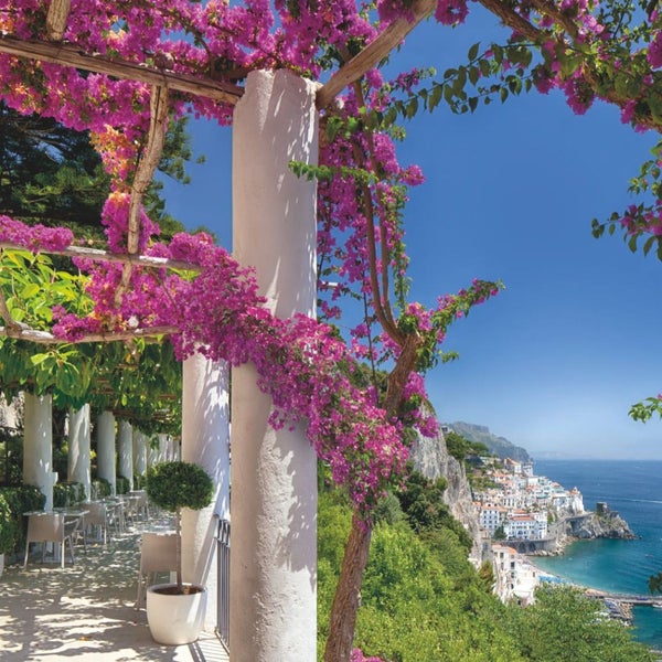 Terrasse mit Bougainvillea-Pflanzen, Blick auf das Meer und die Küstenstadt
