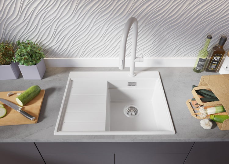 Küchenspüle mit Abtropffläche, Armatur und Lebensmitteln auf einer Arbeitsplatte