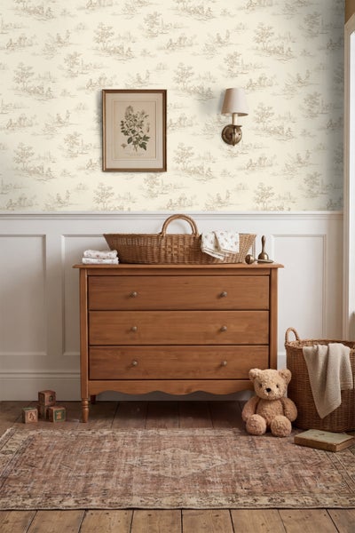 Kinderzimmer mit Holzkommode, Toile-de-Jouy-Tapete, weißer Wandtäfelung, geflochtenen Körben, Teddybär und Wandbild im botanischen Stil.