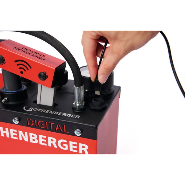 Rothenberger Digital Druckprüfpumpe mit einer Hand, die ein Kabel anschließt