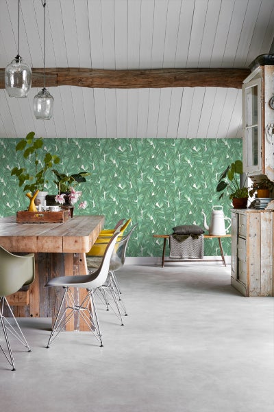 Helles Esszimmer mit Holztisch, Stühlen und einer Wand mit Blättertapete.