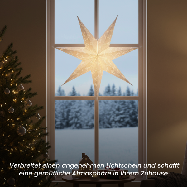 Beleuchteter Papierstern hängt vor einem Fenster, drinnen mit Weihnachtsbaum