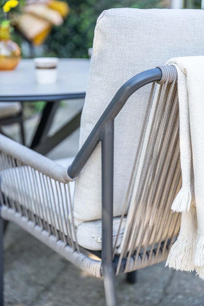 Gartenstuhl aus Metall mit Seilbespannung, Polsterkissen und Wohndecke auf einer Terrasse.