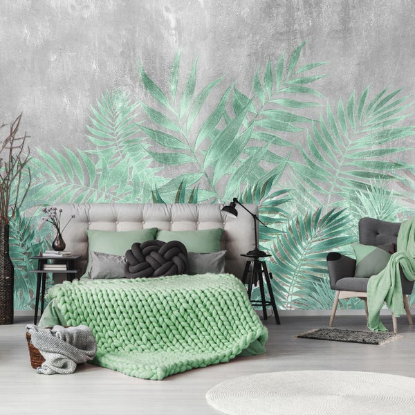 Schlafzimmer mit Wandtapete mit Pflanzenmuster, Bett, Sessel und Beistelltischen.