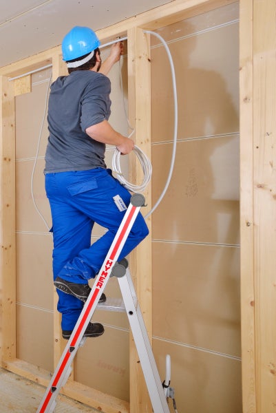 Handwerker auf einer Leiter, der eine elektrische Leitung verlegt.