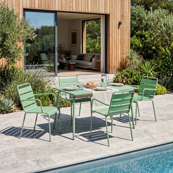 Gartenmöbel-Set aus grünem Metall mit Tisch und vier Stühlen auf Steinterrasse am Pool vor modernem Haus mit Holzfassade.