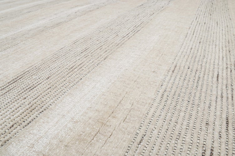 Hocker mit gepolstertem Sitz und Holzbeinen auf einem strukturierten Teppich mit Streifenmuster.