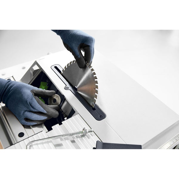 Eine Person mit Handschuhen wechselt das Sägeblatt einer Tischkreissäge.