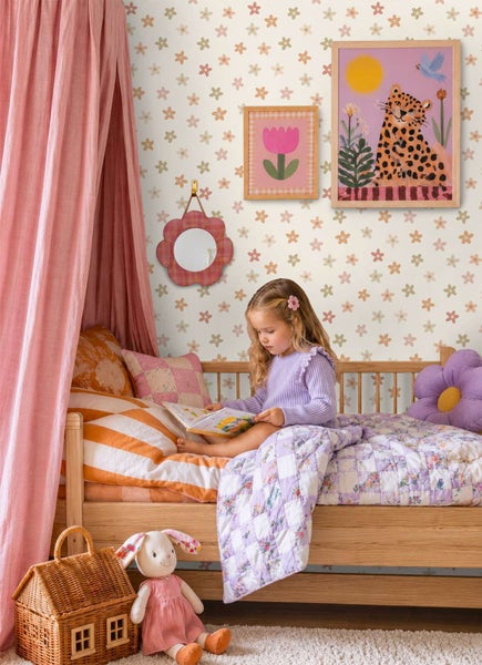 Kinderschlafzimmer mit geblümter Tapete, Holzbett, rosa Betthimmel, Dekoration und einem Mädchen beim Lesen im gemütlichen Ambiente.