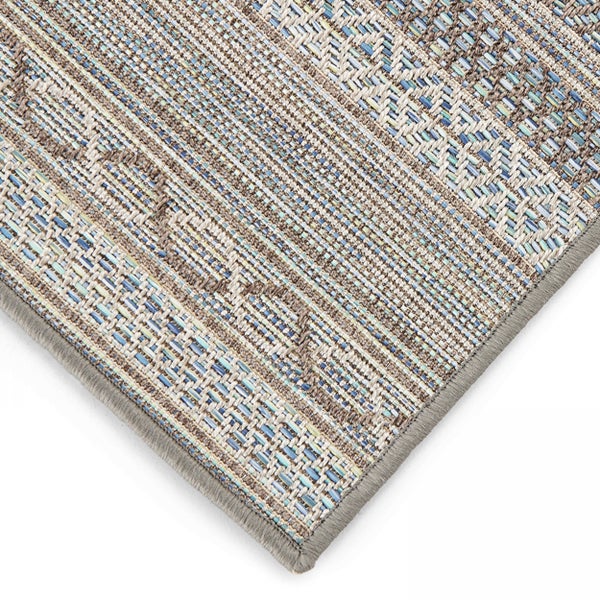 Detailansicht der Ecke eines flachgewebten Indoor- und Outdoor-Teppichs mit geometrischem Muster und geketteltem Rand.
