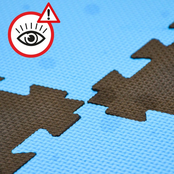 Detailansicht von ineinandergreifenden Schaumstoff Puzzlematten mit Warnhinweis Symbol.