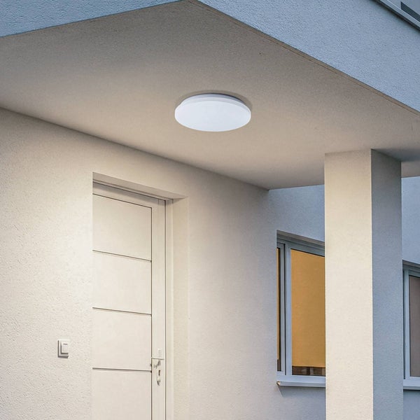 Moderne runde weiße Außen-Deckenleuchte montiert an der Decke im Eingangsbereich eines Wohnhauses.