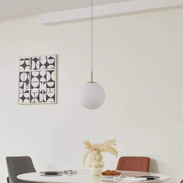 Moderne Pendelleuchte mit weißer Glaskugel und goldfarbener Halterung über einem Esstisch in einem hellen, minimalistischen Raum.