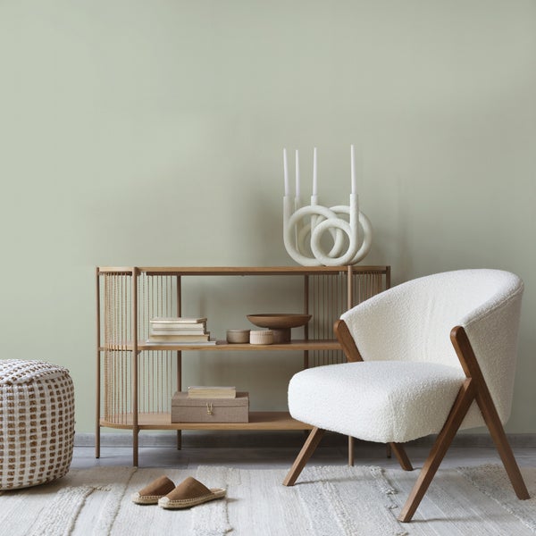 Einrichtungsgegenstände wie ein Regal, ein Sessel und ein Teppich in einem Zimmer