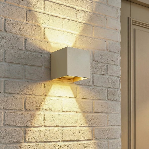 Moderne quadratische Wandleuchte mit Up and Down Lichteffekt an einer hellen Backsteinwand montiert.