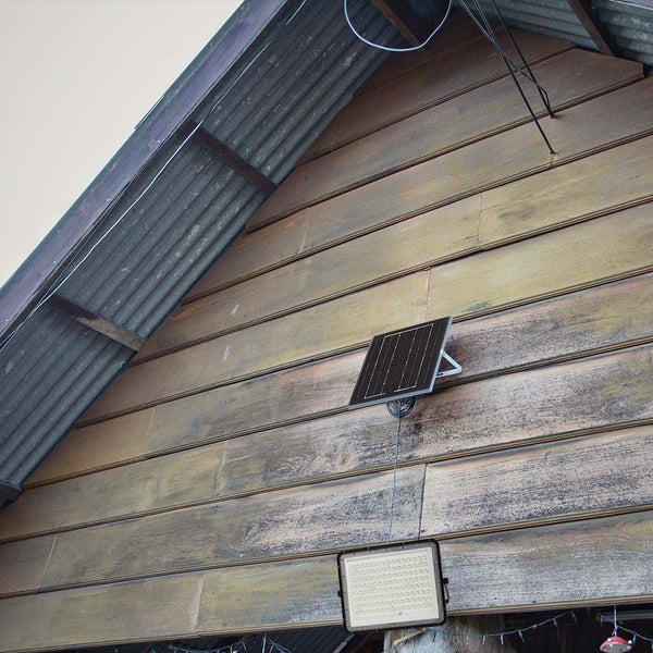 Solarpanel und LED-Strahler an einer Holzwand montiert