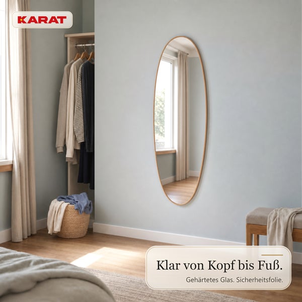 Ovaler Ganzkörperspiegel mit Holzrahmen an einer hellen Wand in einem Ankleidezimmer, Karat Logo.