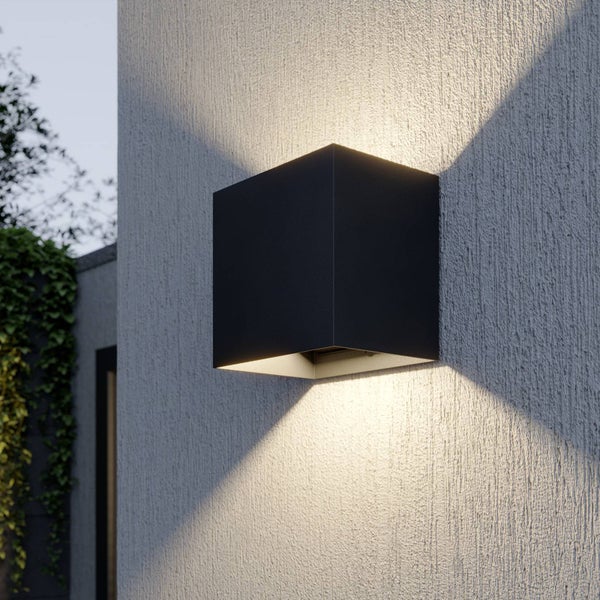 Moderne quadratische Wandleuchte für den Außenbereich mit Lichtaustritt nach oben und unten an einer strukturierten Hauswand.