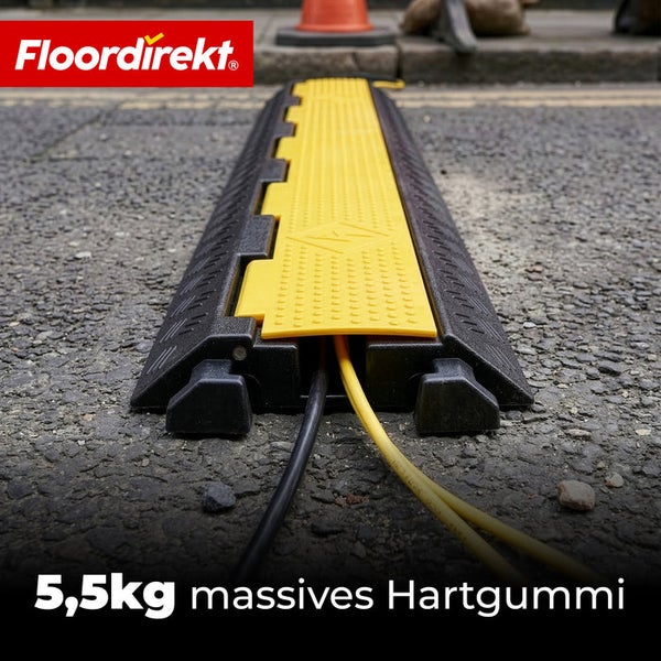 Floordirekt Logo. Kabelbrücke aus 5,5 Kilogramm massivem Hartgummi mit gelber Abdeckung und verlegten Kabeln.