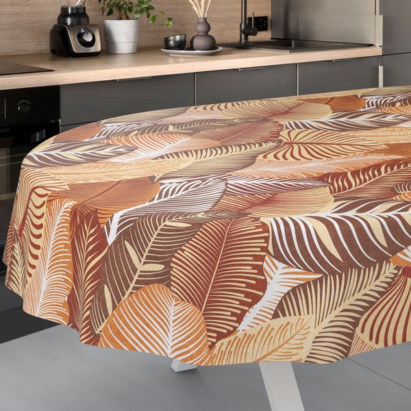 Runde Tischdecke mit Blättermuster in Braun- und Beigetönen auf einem Tisch in einer modernen Küche.