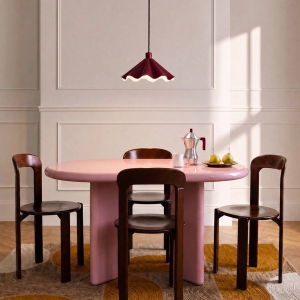 Ein elegantes Esszimmer mit einem runden Tisch und Holzstühlen unter einer modernen Hängeleuchte mit wellenförmigem Lampenschirm.