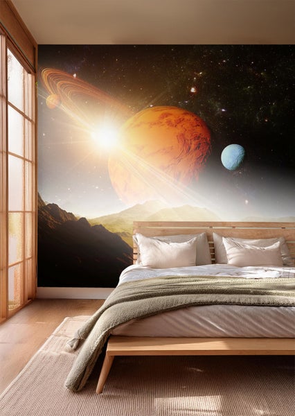 Raum mit einem Bett vor einer Fototapete mit Planetenmotiv.