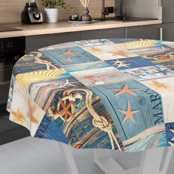 Rundes Tischtuch mit maritimem Patchwork-Muster aus Seesternen, Seilen und Holzoptik in einer Küche.
