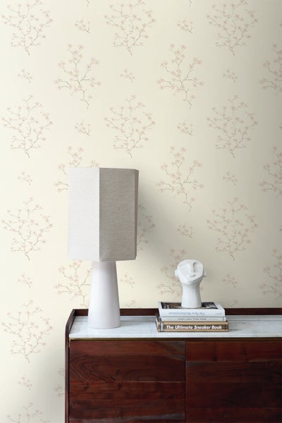 Raumansicht mit Blumentapete, Tischleuchte und Dekoration auf einem Schrank