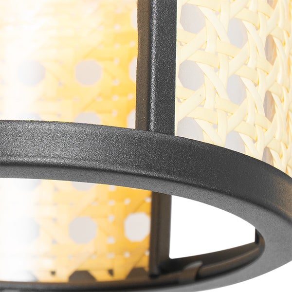 Detailansicht einer Lampe mit Rattanmuster und Metallrahmen