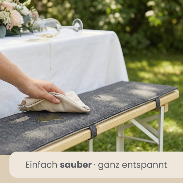Person reinigt eine Sitzauflage für Festzeltgarnituren auf einer Holzbank im Garten mit einem Tuch.