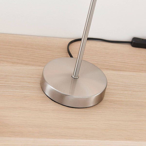 Runder Lampenfuß aus gebürstetem Metall auf einer Holzoberfläche mit schwarzem Kabel.