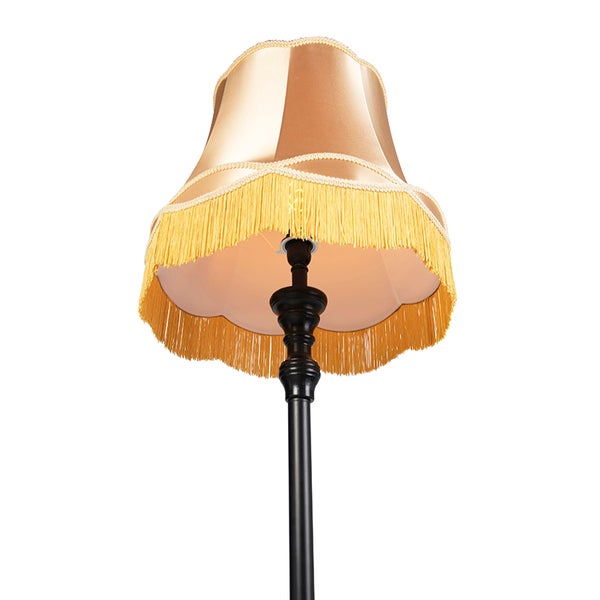 Klassische Stehleuchte mit goldenem Textilschirm, Fransen und schwarzem Standfuß im Vintage-Design.